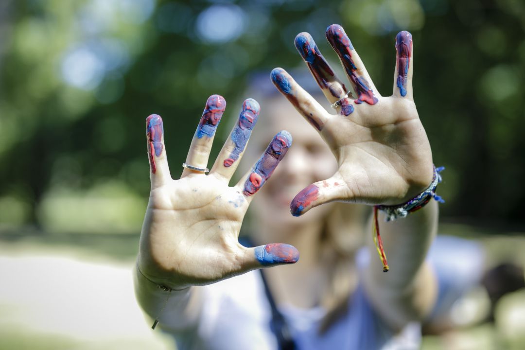Zwei H&auml;nde mit bunt bemalten Fingerspitzen werden in die Kamera gehalten.