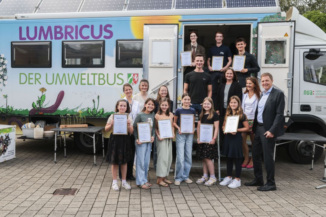 Die Preistr&auml;ger:innen des Wettbewerbes stehen vor dem Umweltbus der NUA NRW