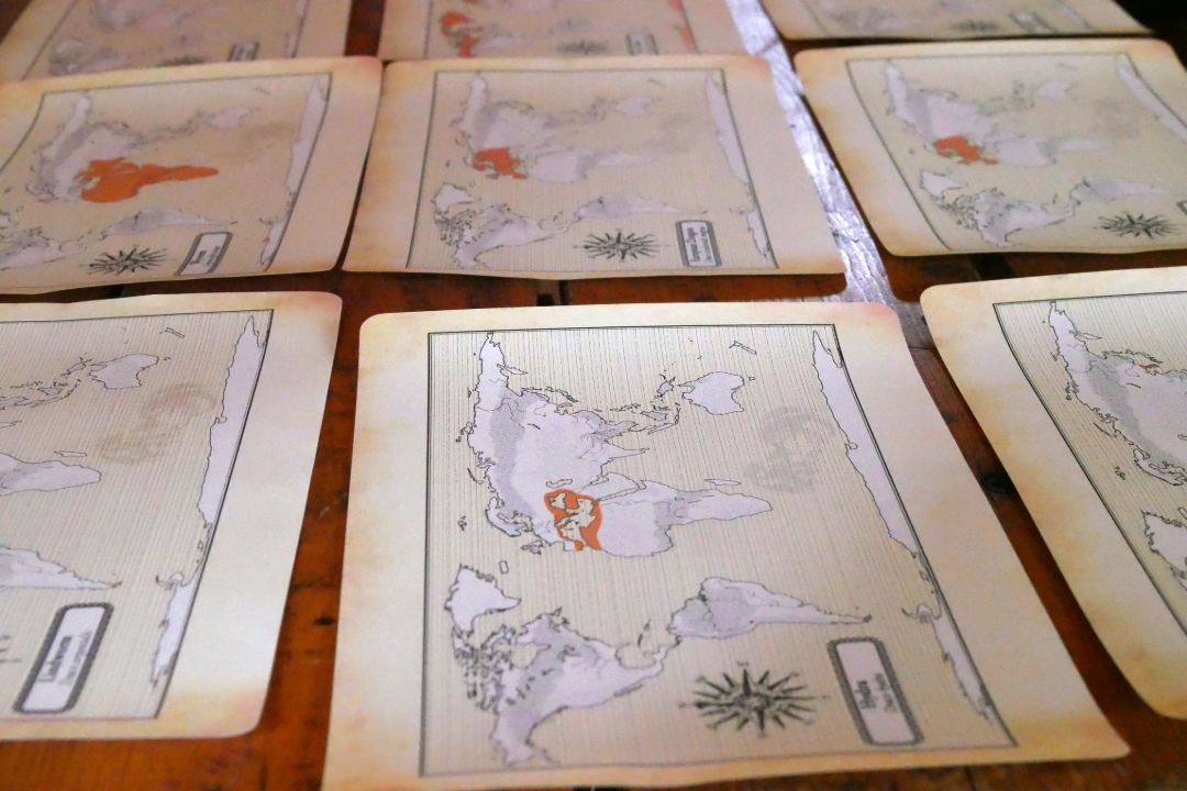Es liegen 9 ausgedruckte historische Weltkarten auf einem Tisch