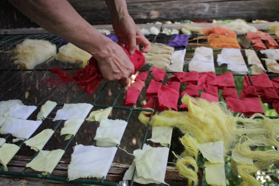 Es sind verschiedene bunte Stofft&uuml;cher, die mit Pflanzenfarben gef&auml;rbt wurden, auf einem W&auml;schest&auml;nder zu sehen.