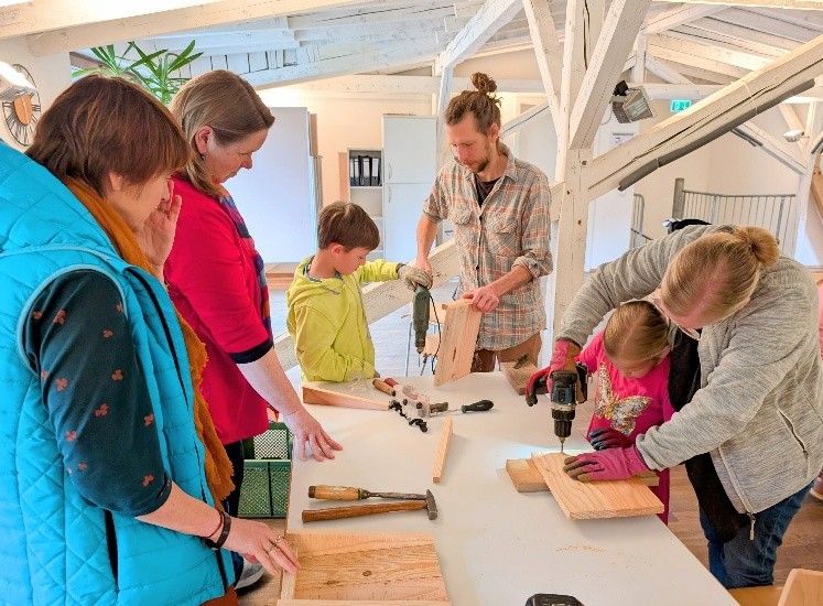 Kinder und Erwachsene bauen gemeinsam Fledermausk&auml;sten indem sie s&auml;gen und schrauben.
