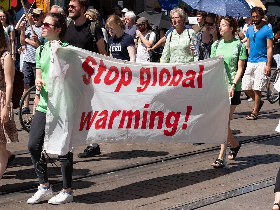 Personen demonstrieren mit einem Plakat "Stop global warming"