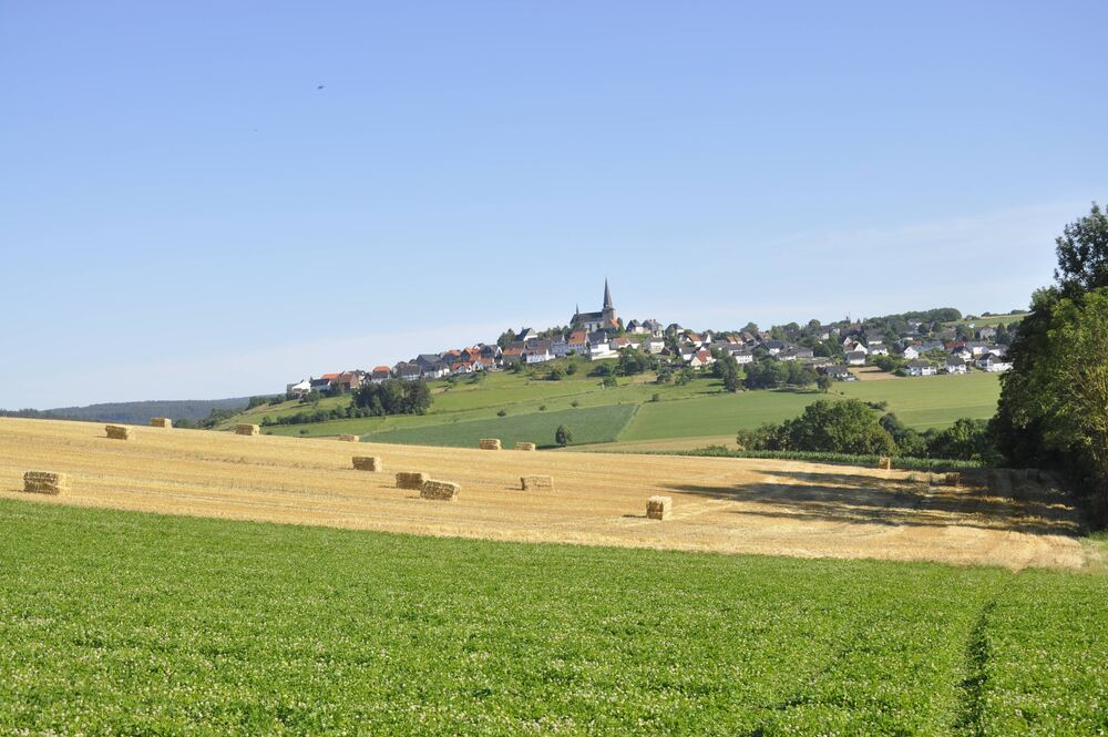 Ackerland und Dorf mit Kirche im Hintergrund