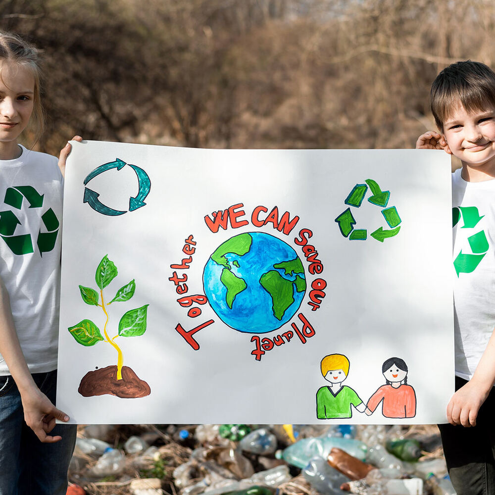 Zwei Kinder halten ein Papier-Plakat hoch, auf dem steht: Together we can save our planet