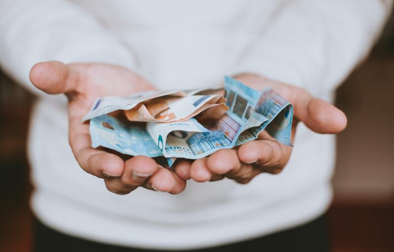 Ein junger Mensch hält 20 €- und 50 €-Scheine in seinen Händen.