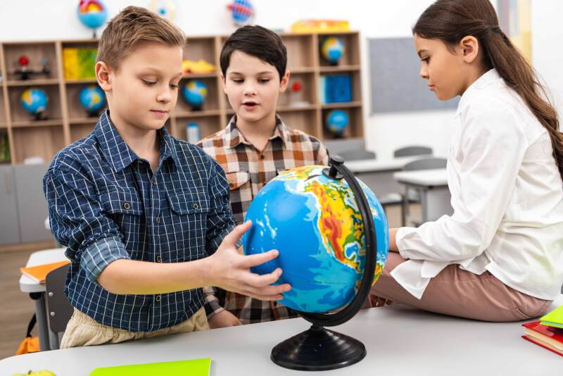 Kinder lernen mit Hilfe eines Globus. 